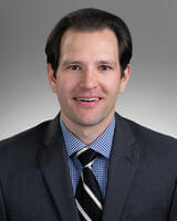 Robert Steininger with short dark hair wearing formal suit and tie