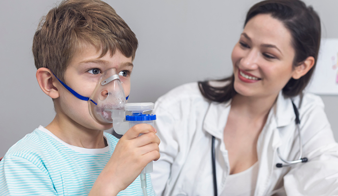 young boy using a breathing mask with a doctor