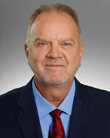 Headshot of Dr. Haaland with a blue shirt and red tie