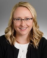 Jordan Bleth wearing black and white with glasses and medium long blonde hair