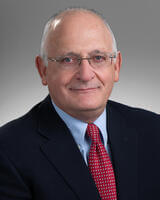 headshot of Dr. deLeeuw with a black jacket, red tie, and glasses