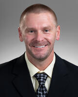 Headshot of Matt Linback in dark suit with yellow tinted shirt