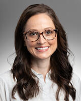 Headshot of Shannon Peters with dark hair, glasses, and white shirt.