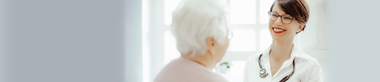 A smiling provider with an elderly patient
