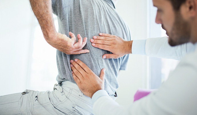 chiropractor looking at a mans back