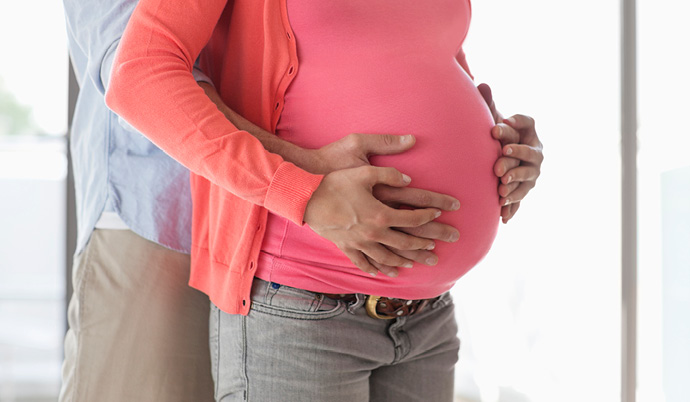 couple embracing pregnant womans belly