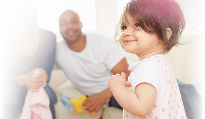 little girl smiling up with parents