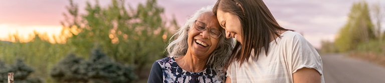 Mother and daughter smiling as they walk outside during a sunset