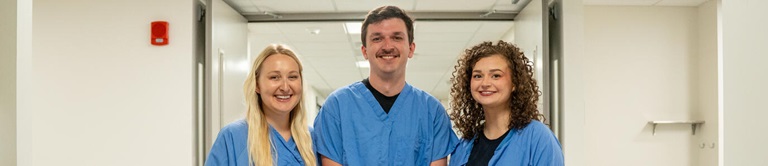 Three nurses smiling in the hallway.