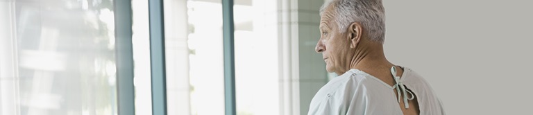 man in hospital gown looking out window