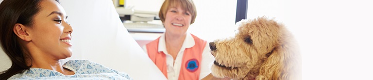 patient interacting with a dog from hospital bed